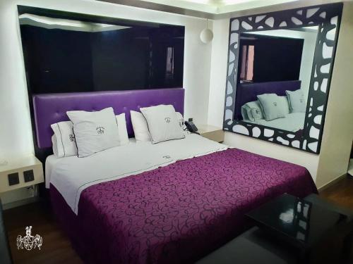 墨西哥城Hotel Del Valle的一间卧室配有一张紫色的床和一面大镜子
