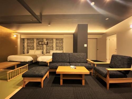 福冈Randor Residential Hotel Fukuoka Annex的酒店客房设有两张床、一张沙发和一张桌子。