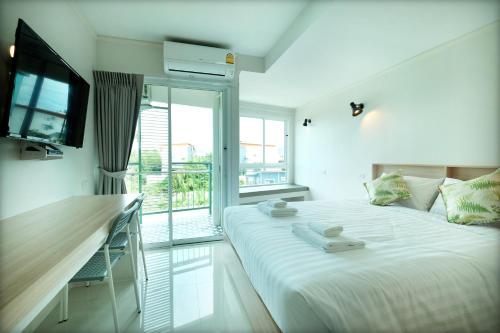 奈扬海滩beHOME Phuket的一间白色卧室,配有床和阳台