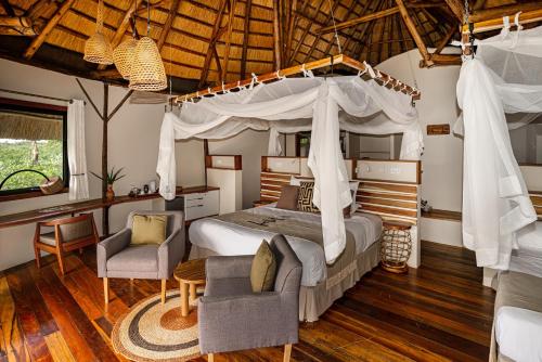 KangulumiraLemala Wildwaters Lodge的一间卧室配有一张天蓬床和两把椅子