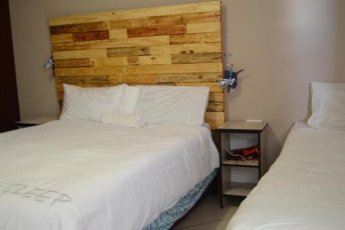 温特和克Sharon Rose Guesthouse的一间卧室设有两张床和木制床头板