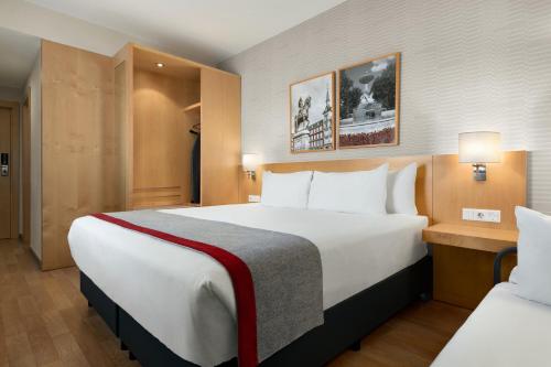 赫塔费Ramada by Wyndham Madrid Getafe的酒店客房带一张大床和一把椅子