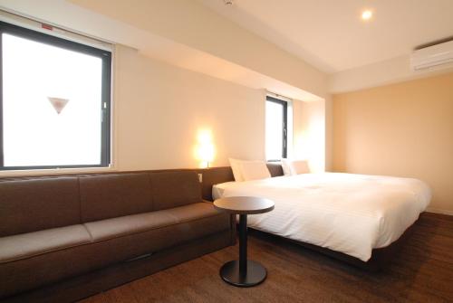 伊势崎市AB Hotel Isesaki的一间卧室配有一张床、一张沙发和一个窗口