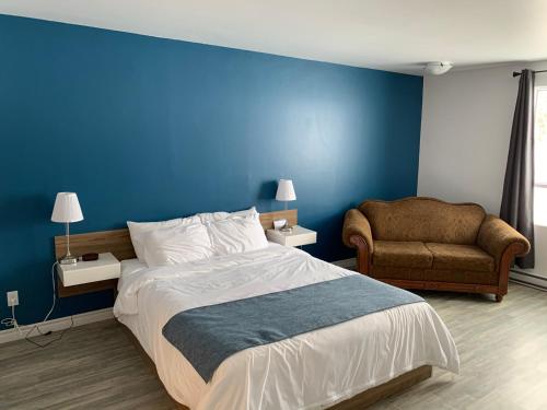 MetabetchouanMotel Le Rond Point的一间卧室设有蓝色的墙壁、一张床和一把椅子