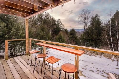 斯托Classic Stowe Ski Chalet chalet的甲板上配有凳子和桌子的门廊