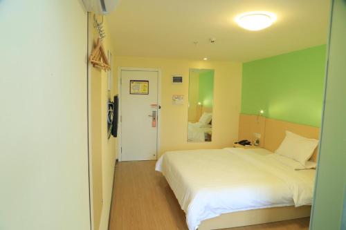 贵阳7Days Inn Guiyang Ergezhai的卧室配有白色的床和绿色的墙壁