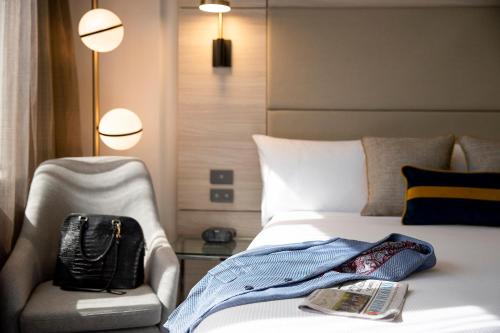 悉尼诺富特悉尼帕拉马塔酒店的酒店客房,配有床、椅子和书