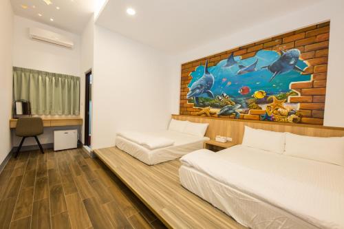 小琉球岛小琉球八八民宿的一间卧室设有两张床,墙上挂着一幅画
