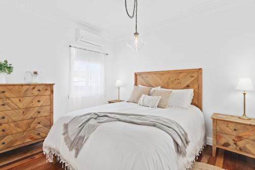 CanungraThe Cottage on Lamington的白色卧室设有一张带木制床头板的大床
