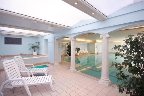 兰迪德诺经典英国帝国酒店的一个带两把白色椅子的游泳池和一个游泳池