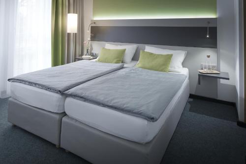 纽伦堡布福特霍特及会议中心酒店的卧室配有带绿色枕头的大型白色床