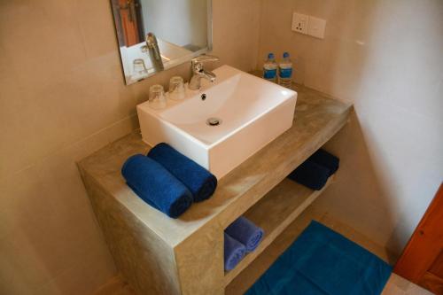 DemanhandiyaJackland Holiday Cabanas的浴室设有水槽和带蓝色毛巾的台面。