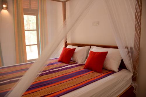 DemanhandiyaJackland Holiday Cabanas的一间卧室配有一张带红色枕头的床和一扇窗户