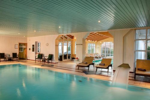 巴特比恩巴赫昆兰霍夫酒店的大楼内带桌椅的大型游泳池