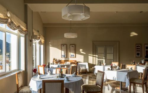 塔维亚诺勒斯维克绍旅馆的餐厅设有白色的桌椅和窗户。