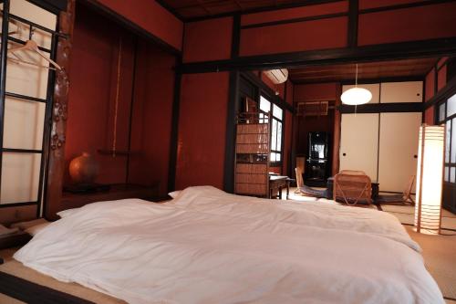 广岛一棟貸ゲストハウス 傾㐂屋 Kabukiya的一张大床,位于红色墙壁的房间