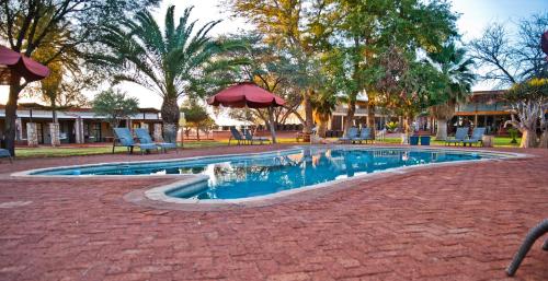 HardapKalahari Anib Campsite的公园内一个带椅子和遮阳伞的游泳池