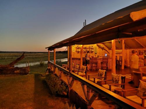 NgomaChobe River Campsite的木甲板上设有桌椅的餐厅