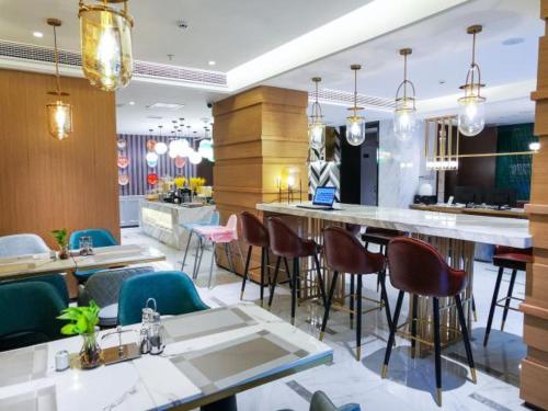 贵阳Magnotel guiyang fountain commercial center subway station hotel的一间带桌椅的餐厅和一间酒吧