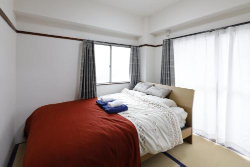 东京G&R House 201的一间卧室配有一张带红色毯子的床