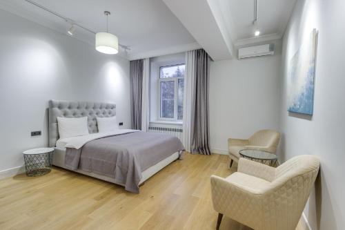 阿拉木图Opera Apartments Almaty的一间卧室配有一张床、两把椅子和一个窗户