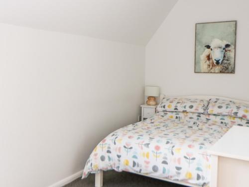 AttlebridgeTricker's Cottage的卧室配有一张床铺,墙上挂着羊的照片