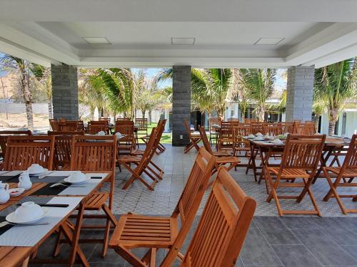 潘切Starlight Villa Beach Resort & Spa的餐厅拥有木桌和椅子,并种植了棕榈树。