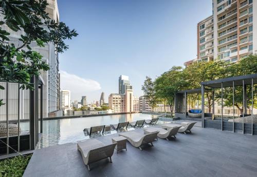 曼谷曼谷橡树套房酒店的一座带椅子的屋顶露台和一座位于大楼内的游泳池