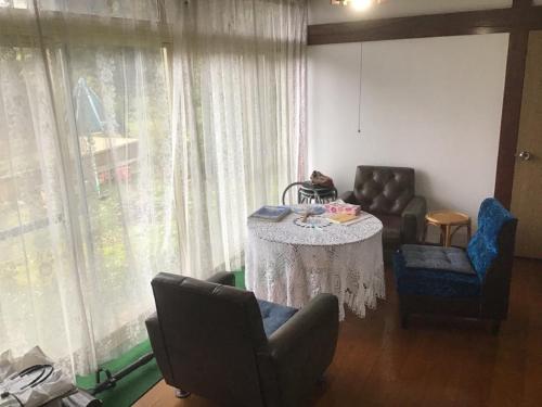 鹤冈市Ohanabatake的客厅配有桌椅和窗帘