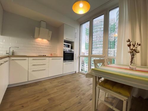 克里扎尼夫卡Scandinavian apartment на Марсельской的厨房配有白色橱柜和餐桌