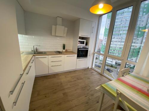 克里扎尼夫卡Scandinavian apartment на Марсельской的一间厨房,配有白色的橱柜和大窗户