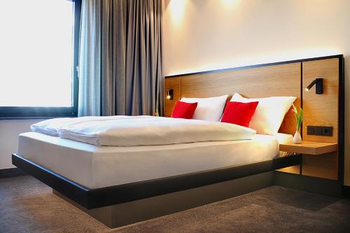 拉芬斯堡GINN City and Lounge Ravensburg的一间卧室配有一张带红色枕头的大床