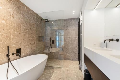奥斯坦德Hyper-Luxeappartement, zeezicht, centrum, airco, optie hotelservices的带浴缸、两个盥洗盆和淋浴的浴室。