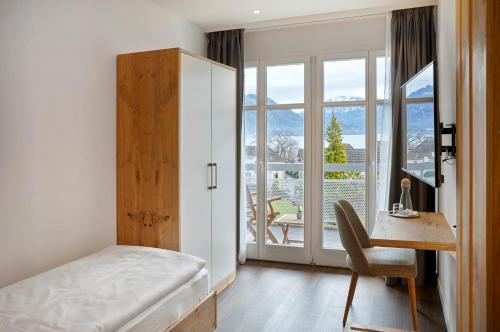 韦吉斯Hotel Rössli Gourmet & Spa的一间卧室配有一张床、一张书桌和一个窗户。