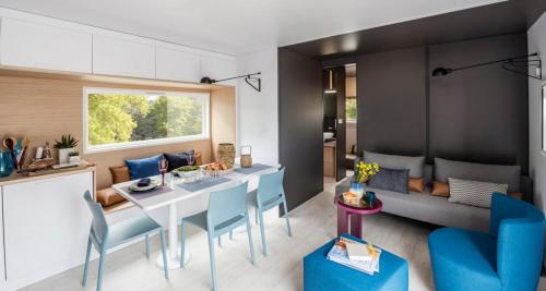 梅拉Camping Le Ventadour的厨房以及带桌子和蓝色椅子的客厅。