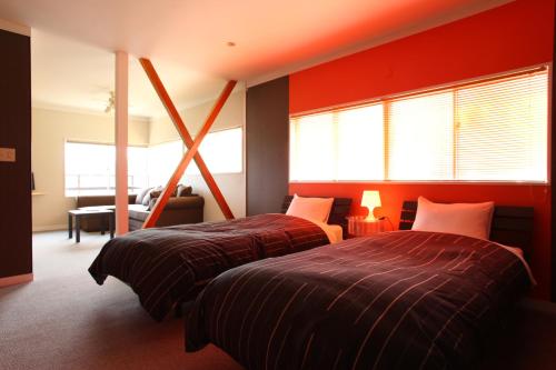 伊东休闲海滩公社（仅限成人）的宿舍间的两张床,设有红色的墙壁和窗户