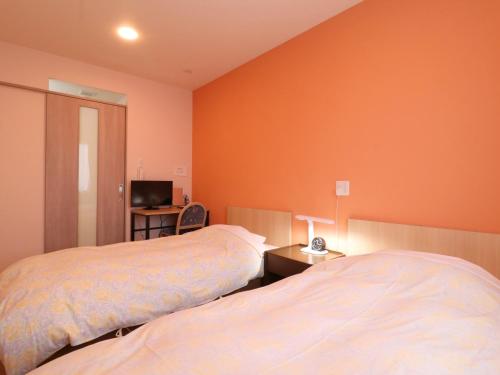 府中市府中旭格兰杜尔经济型酒店的橙色墙壁客房的两张床