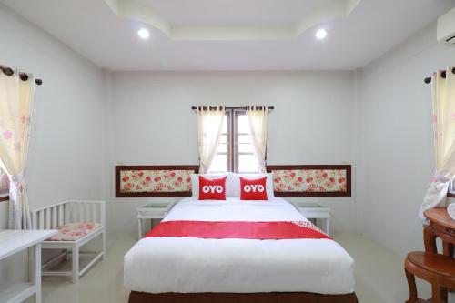 南奔OYO 553 Kongsup Resort的一间卧室配有一张带红色和白色床单的大床