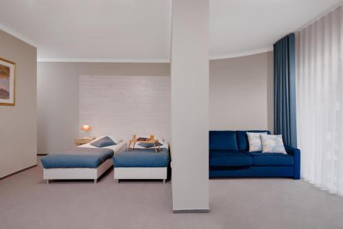 波加茨泽沃Plaża Resort的客厅配有蓝色的沙发和床。