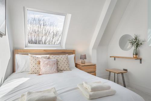 希钦Stylish & Modern: Central Hitchin - with Parking的卧室配有带枕头的白色床和窗户。
