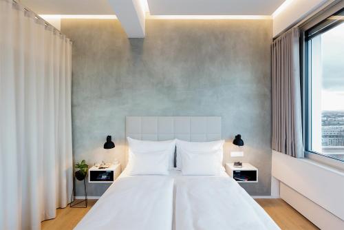 维也纳维也纳菲尔斯普乐斯全方位服务式公寓的卧室设有白色的床和大窗户