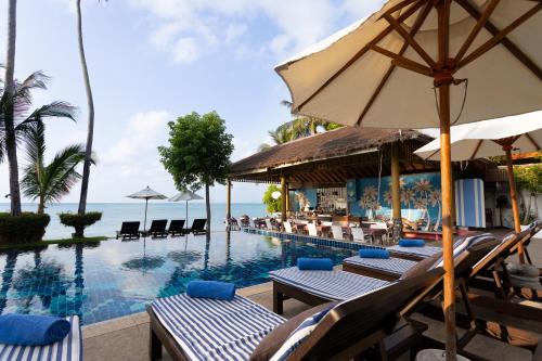 拉迈棕榈可可曼特拉酒店的一个带椅子和遮阳伞的度假村游泳池