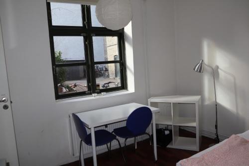 哥本哈根Charming Red Courtyard Apartment的客房设有书桌、两把椅子和窗户。