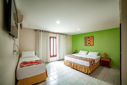 格拉瓦塔Hotel Três Palmeiras的绿墙客房内的两张床