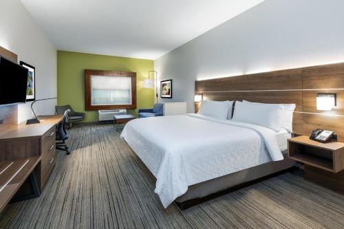 章克申Holiday Inn Express & Suites Junction, an IHG Hotel的一间酒店客房,配有一张大床和一台平面电视