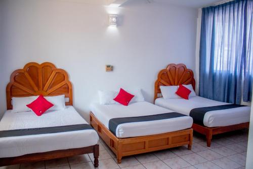 锡瓦塔塔内霍Hotel Adelita的宿舍间的三张床,配有红色枕头