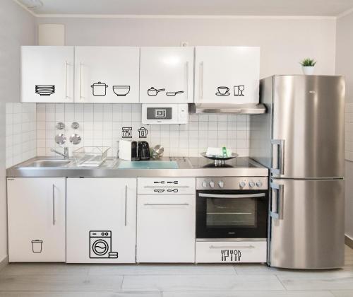 慕尼黑ARABEST Aparthotel & Boardinghouse的厨房配有白色橱柜和不锈钢冰箱
