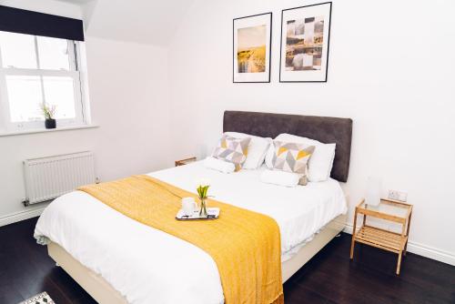 科尔切斯特Detached Coach House的白色卧室配有一张黄色毯子床