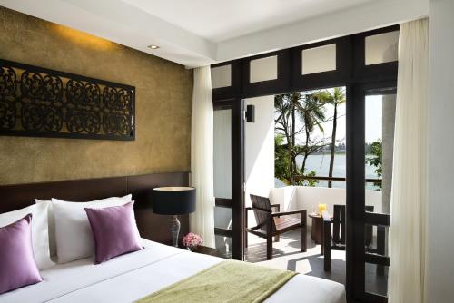 卡卢特勒Avani Kalutara Resort的一间卧室配有一张带紫色枕头的床和一个阳台