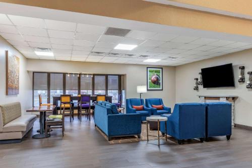 克莱门森Comfort Inn & Suites Clemson - University Area的一间设有蓝色桌椅和电视的等候室